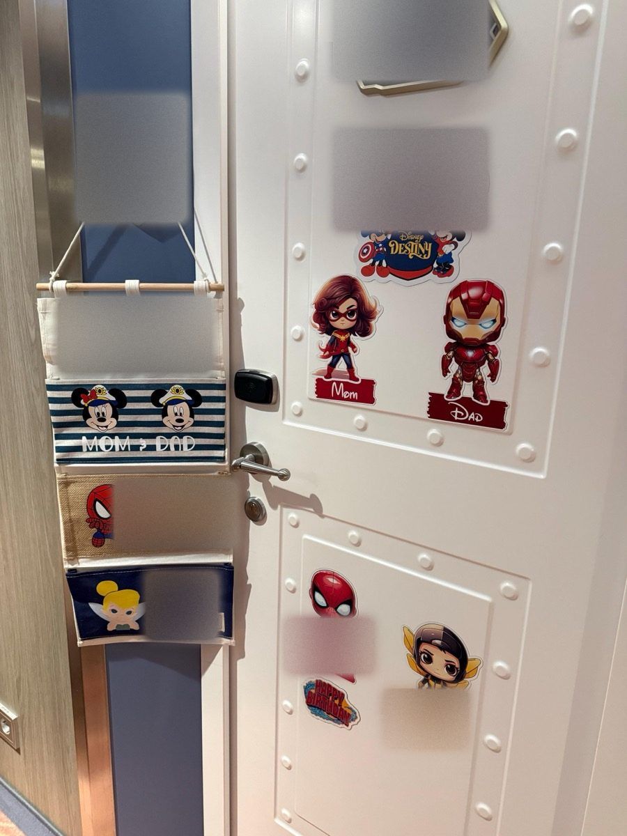 A navy-stripe fish extender reading Mom & Dad, hanging next to a door full of superhero magnets